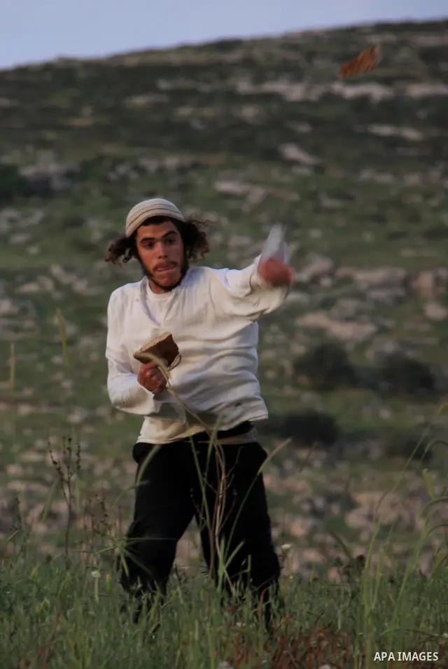 A Jewish settler from the Har Bracha settlement holds stones as he readies to lob them at local Palestinian villagers during clashes close to the Palestinian village of Burin in the Israeli occupied West bank on April 19...