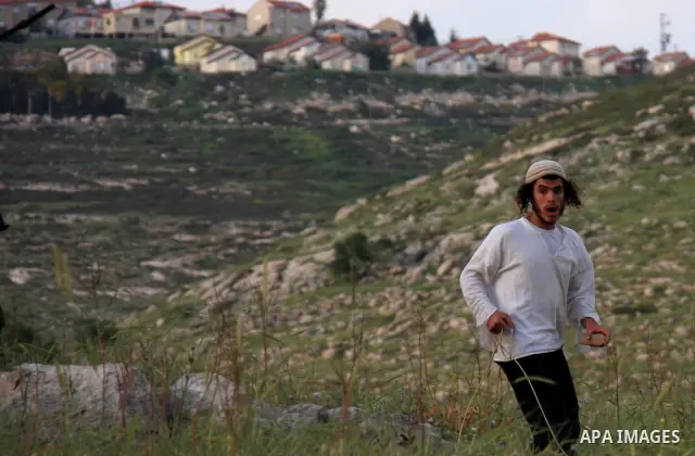 A Jewish settler from the Har Bracha settlement holds stones as he readies to lob them at local Palestinian villagers during clashes close to the Palestinian village of Burin in the Israeli occupied West bank on April 19...