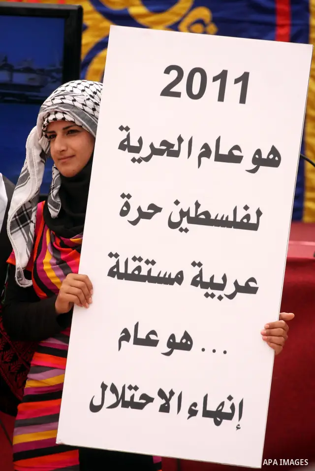 A Palestinian girl holds up slogans during the opening ceremony of the 6th Bilin international conference for Palestinian Popular Resistance on April 20, 2011 in West Bank village of Bilin, near Ramallah. Fayyad called o...
