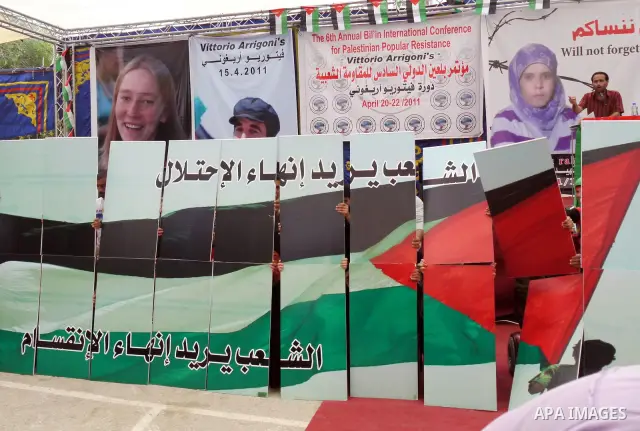 Palestinians hold up placards in the colors of their national flag during the opening ceremony of the 6th Bilin international conference for Palestinian Popular Resistance on April 20, 2011 in West Bank village of Bilin,...