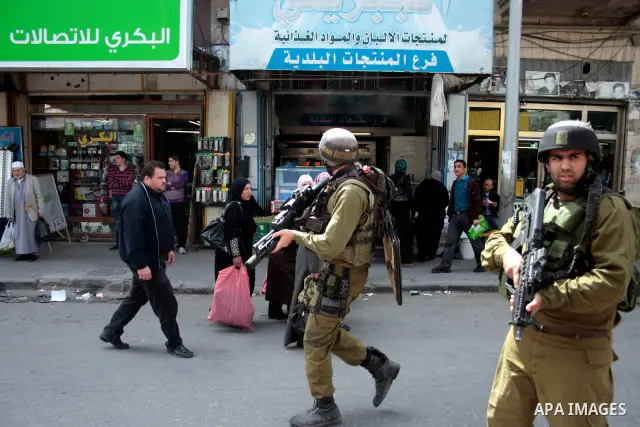 Israeli soldiers stand guard in an empty street in Hebron in the occupied West Bank on April 20, 2011. The Israeli army imposed a temporary curfew on Palestinians in the city centre to allow Jewish settlers to visit the...