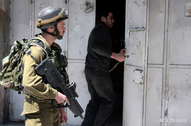 Israeli soldiers stand guard in an empty street in Hebron in the occupied West Bank on April 20, 2011. The Israeli army imposed a temporary curfew on Palestinians in the city centre to allow Jewish settlers to visit the...