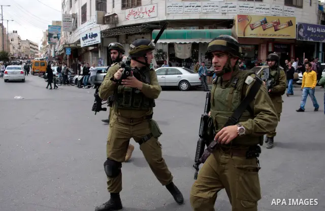 Israeli soldiers stand guard in an empty street in Hebron in the occupied West Bank on April 20, 2011. The Israeli army imposed a temporary curfew on Palestinians in the city centre to allow Jewish settlers to visit the...