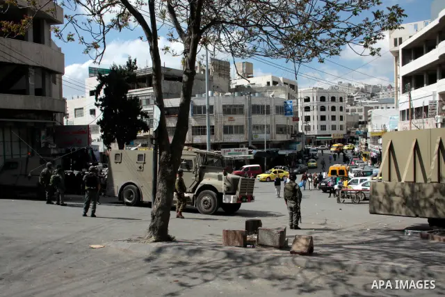 Israeli soldiers stand guard in an empty street in Hebron in the occupied West Bank on April 20, 2011. The Israeli army imposed a temporary curfew on Palestinians in the city centre to allow Jewish settlers to visit the...
