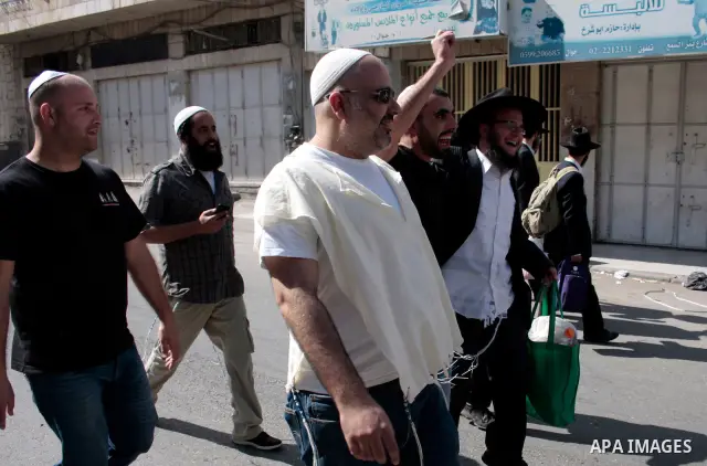 Israeli settlers walk in an empty street in Hebron in the occupied West Bank on April 20, 2011.The Israeli army imposed a temporary curfew on Palestinians in the city centre to allow Jewish settlers to visit the tomb of...