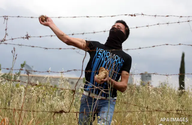 A Palestinian protester hurls stones toward Israeli soldiers during the weekly demonstration against Israel's controversial separation barrier in the village of Bilin, near the West Bank city of Ramallah on April 22, 201...