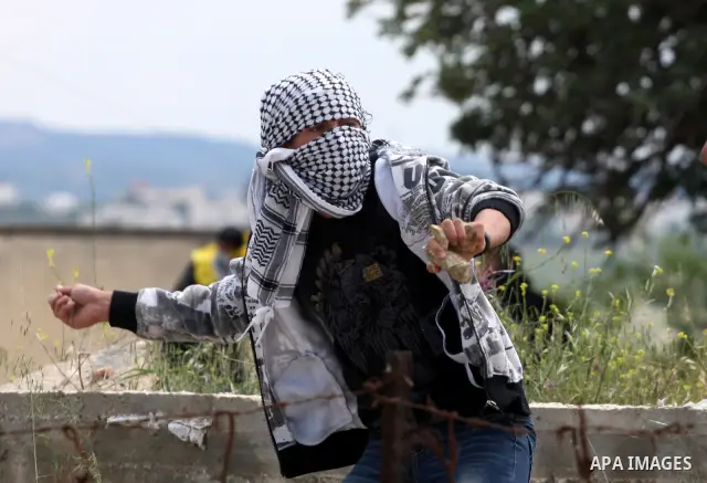 A Palestinian protester hurls stones toward Israeli soldiers during the weekly demonstration against Israel's controversial separation barrier in the village of Bilin, near the West Bank city of Ramallah on April 22, 201...