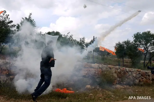 A Palestinian protester runs for cover from tear gas canisters fired by Israeli soldiers during the weekly demonstration against Israel's controversial separation barrier in the village of Bilin, near the West Bank city...
