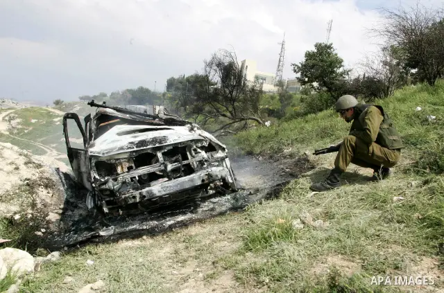 Israeli soldiers stand guard near a burnt Israeli army vehicle on April 22, 2011 after it flipped over and was set alight by Palestinian youths in the flashpoint neighbourhood of Issawiya in annexed east Jerusalem. No in...