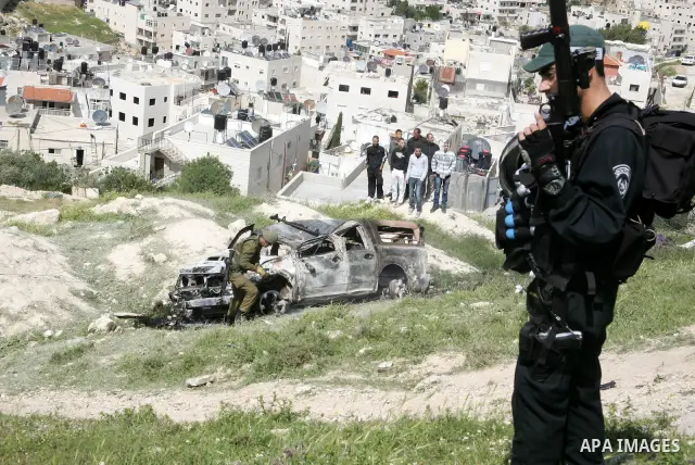 Israeli soldiers stand guard near a burnt Israeli army vehicle on April 22, 2011 after it flipped over and was set alight by Palestinian youths in the flashpoint neighbourhood of Issawiya in annexed east Jerusalem. No in...
