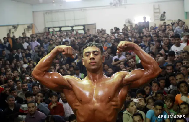 Palestinian men take part during competing in a bodybuilding contest at a hall in Gaza city, Friday, April 22, 2011. Many of the men use women's cosmetics, mud, or paint to enhance their muscles. Number of men from aroun...