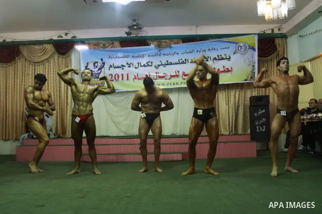 Palestinian men take part during competing in a bodybuilding contest at a hall in Gaza city, Friday, April 22, 2011. Many of the men use women's cosmetics, mud, or paint to enhance their muscles. Number of men from aroun...