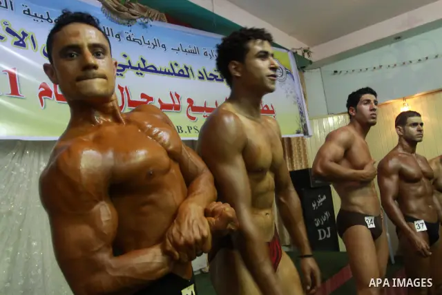 Palestinian men take part during competing in a bodybuilding contest at a hall in Gaza city, Friday, April 22, 2011. Many of the men use women's cosmetics, mud, or paint to enhance their muscles. Number of men from aroun...