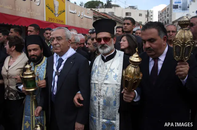 Palestinian prime minister Salam Fayyad holds a latern containing the 'Holy Fire' brought from the Church of the Holy Sepulchre in Jerusalem during a parade making the 'Holy Fire' ceremony on the eve of the Orthodox East...
