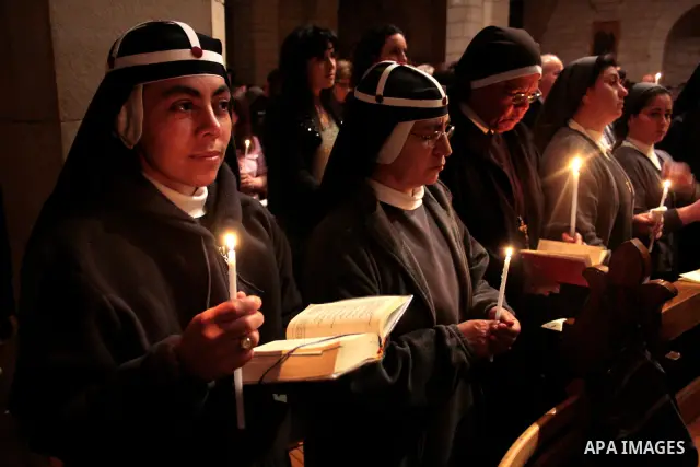 A Catholic priest lights a Paschal candle inside the Church of the Nativity compound at the opening of the Easter Vigil on Holy Saturday late April 23, 2011 in the West Bank town of Bethlehem. Christians of the western c...
