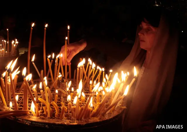 Christian woman lights candles during the Sunday mass in the Church of the Nativity in the holy West Bank town of Bethlehem April 24, 2011.The church is built over the grotto where Christians believe the Virgin Mary gave...