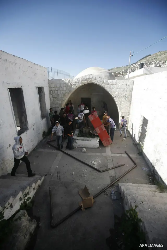 Palestinian youths take cover inside the entrance to the shrine of Joseph's Tomb in the West Bank city of Nablus on April 24, 2011 as clashes erupted after an Israeli worshipper was shot dead by Palestinian policemen nea...