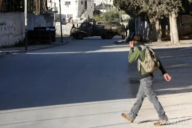 Palestinian youth throw stones towards Israeli soldiers patrolling near the shrine of Joseph's Tomb in the West Bank city of Nablus on April 24, 2011 as clashes erupted after an Israeli worshipper was shot dead by Palest...