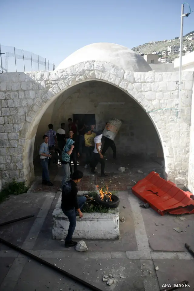 Palestinian youths take cover inside the entrance to the shrine of Joseph's Tomb in the West Bank city of Nablus on April 24, 2011 as clashes erupted after an Israeli worshipper was shot dead by Palestinian policemen nea...