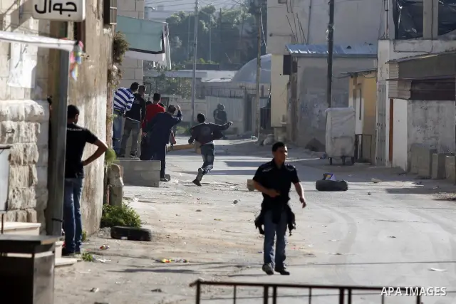 Palestinian youth throw stones towards Israeli soldiers patrolling near the shrine of Joseph's Tomb in the West Bank city of Nablus on April 24, 2011 as clashes erupted after an Israeli worshipper was shot dead by Palest...