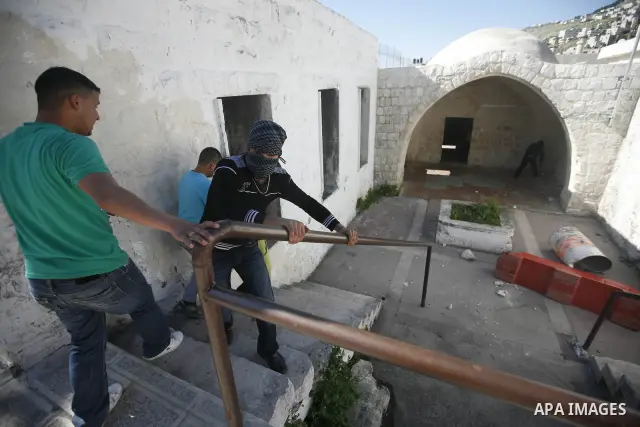 Palestinian youths take cover inside the entrance to the shrine of Joseph's Tomb in the West Bank city of Nablus on April 24, 2011 as clashes erupted after an Israeli worshipper was shot dead by Palestinian policemen nea...