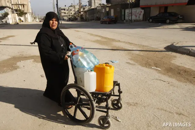 A Palestinian woman fill bottles with water from a public tap in the United Nations Relief and Works Agency (UNRWA) headquarters in Rafah refugee camp in the southern of Gaza strip on April 26, 2011. Photo by Abed Rahim...