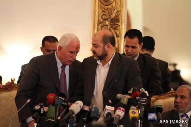 Palestinian Fatah delegation chief Azzam al-Ahmed shakes hands with Hamas deputy leader Mussa Abu Marzuq after a joint press conference in Cairo on April 27, 2011 as the rival Palestinian groups reached an "understanding...