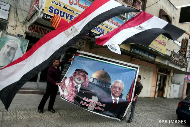 Palestinian men carry a poster for the Palestinian President Mahmoud Abbas and Palestinian Prime Minister in Gaza Strip, Ismail Hanieyah, in Gaza City on April 28, 2011 as Palestinians in the Gaza Strip and the West Bank...
