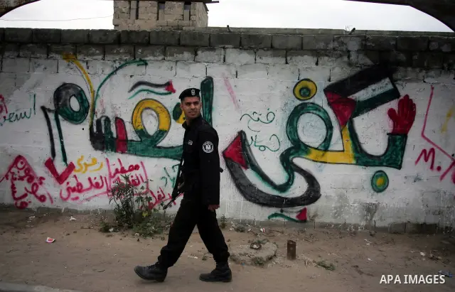 A Palestinian policeman walks past graffiti reading in Arabic, "Yes to the end of the division", in Gaza City on April 28, 2011 as Palestinians in the Gaza Strip and the West Bank welcomed reports that their rival Hamas...