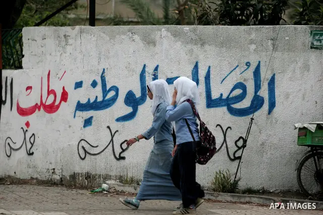 Palestinian girlschool walk past graffiti reading in Arabic, "Yes to the end of the division", in Gaza City on April 28, 2011 as Palestinians in the Gaza Strip and the West Bank welcomed reports that their rival Hamas an...