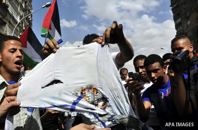 Egyptian protesters burn the Israeli flag and wave the Palestinian flag during a demonstration in front of the Israeli embassy in Cairo on April 29, 2011, calling for opening the border with the Gaza Strip and in support...