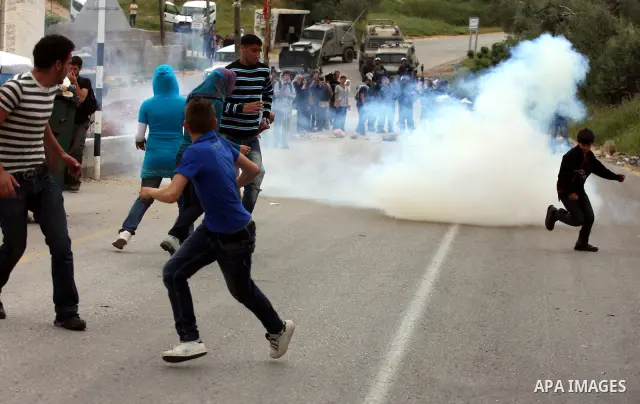 Demonstrators run for cover from tear gas fired by Israeli soldiers during protest against the expropriation of Palestinian land to expand the Jewish settlement of Halmish on April 29, 2011 in the West Bank village of Na...