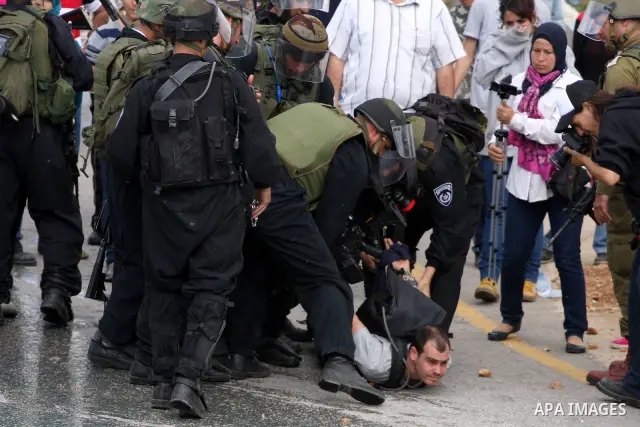 Israeli soldiers detain a pro-Palestinian activist during protest against the expropriation of Palestinian land to expand the Jewish settlement of Halmish on April 29, 2011 in the West Bank village of Nabi Saleh. Photo b...