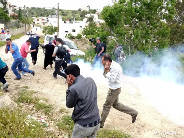 Demonstrators run for cover from tear gas fired by Israeli soldiers during protest against the expropriation of Palestinian land to expand the Jewish settlement of Halmish on April 29, 2011 in the West Bank village of Na...