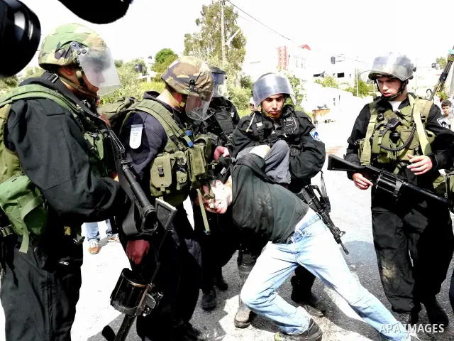 Israeli soldiers detain a pro-Palestinian activist during protest against the expropriation of Palestinian land to expand the Jewish settlement of Halmish on April 29, 2011 in the West Bank village of Nabi Saleh. Photo b...