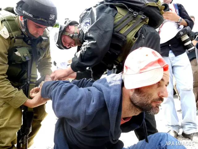 Israeli soldiers detain a pro-Palestinian activist during protest against the expropriation of Palestinian land to expand the Jewish settlement of Halmish on April 29, 2011 in the West Bank village of Nabi Saleh. Photo b...