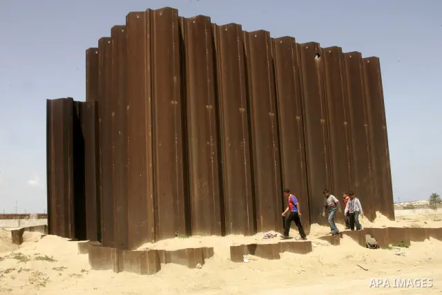 Palestinian boys walk past a segment of what used to be a border fence between Egypt and the Gaza Strip near Rafah on April 30, 2011, a day after Egypt said it will permanently open the Rafah border crossing as part of i...