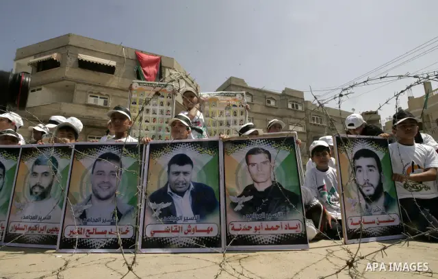 Children sit next to images of Palestinian prisoners being held in Israeli jails during a rally on May 01, 2011, calling for their release in Rafah town in the southern Gaza Strip. Photo by Abed Rahim Khatib