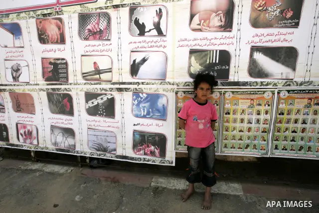 A child sits next to images of Palestinian prisoners being held in Israeli jails during a rally on May 01, 2011, calling for their release in Rafah town in the southern Gaza Strip. Photo by Abed Rahim Khatib