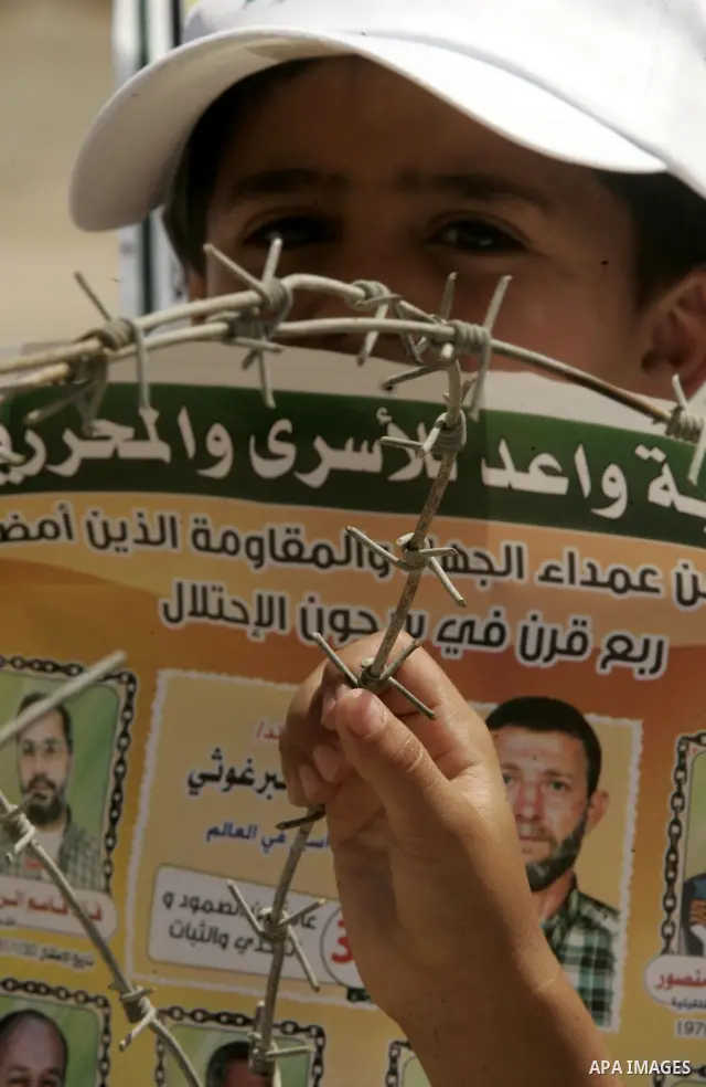 A child holds up images of Palestinian prisoners being held in Israeli jails during a rally on May 01, 2011, calling for their release in Rafah town in the southern Gaza Strip. Photo by Abed Rahim Khatib