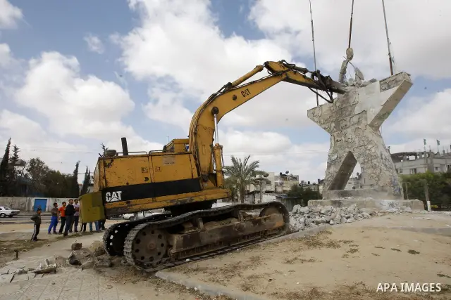 Palestinians look at a bulldozer demolishing a star figure as volunteers from the ruling Islamic Hamas movement took to the street in a project entitled "Gaza is the most beautiful despite the blockade" to mark workers'...