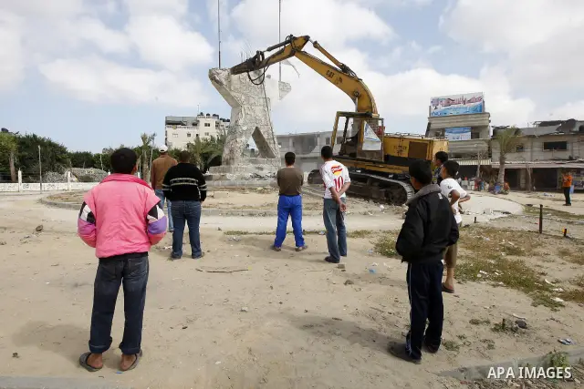 Palestinians look at a bulldozer demolishing a star figure as volunteers from the ruling Islamic Hamas movement took to the street in a project entitled "Gaza is the most beautiful despite the blockade" to mark workers'...