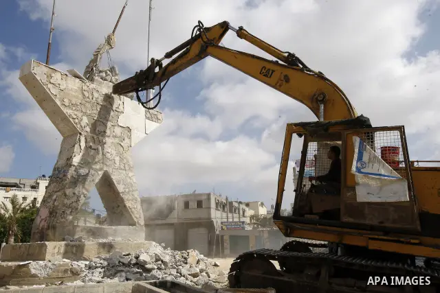 Palestinians look at a bulldozer demolishing a star figure as volunteers from the ruling Islamic Hamas movement took to the street in a project entitled "Gaza is the most beautiful despite the blockade" to mark workers'...