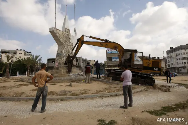 Palestinians look at a bulldozer demolishing a star figure as volunteers from the ruling Islamic Hamas movement took to the street in a project entitled "Gaza is the most beautiful despite the blockade" to mark workers'...