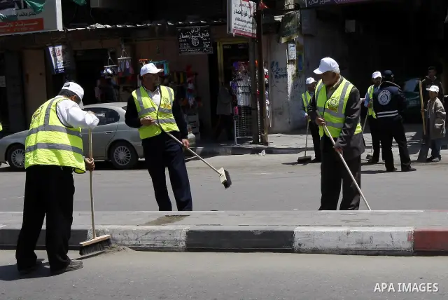 Members of the ruling Islamic Hamas movement sweep the street as volunteers took to the street in a project entitled "Gaza is the most beautiful despite the blockade" to mark workers' May Day in Rafah town In Gaza Strip,...