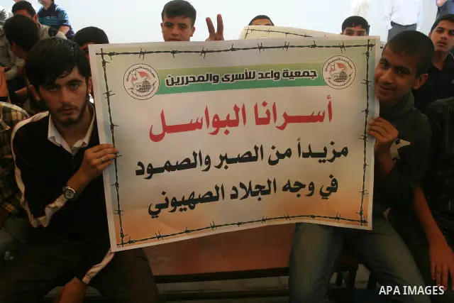 Palestinian women holds a photograph of her relative held in an Israeli jail as she takes part in a hunger strike together with others to show solidarity with their jailed relatives at the headquarters of the Internation...