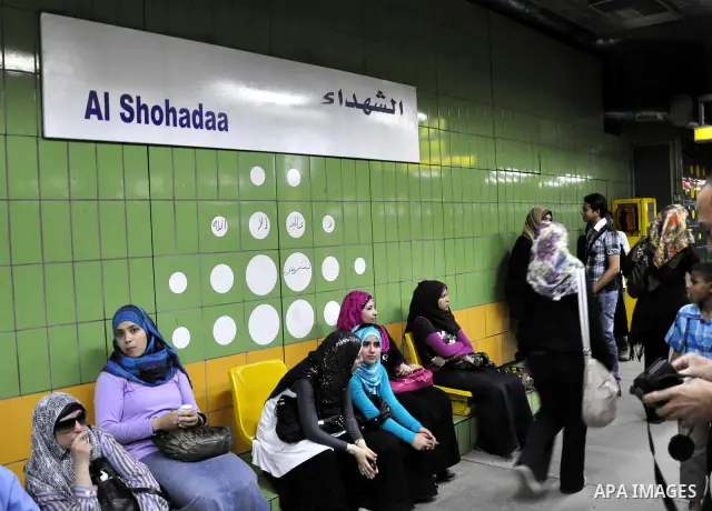 Egyptian women wait at a metro station under a placard holding the name Al Shohadaa "the Martyrs" in Arabic and English in Cairo, Egypt on May 03, 2011. Al Shohadaa is the new name of the metro which called in the past i...