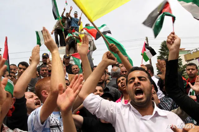 Palestinians wave with national flag and shout slogans during a rally celebrating the signing of a reconciliation deal in Gaza city on May 4,2011. Hundreds of Palestinians have gathered to cheer on a unity agreement bein...