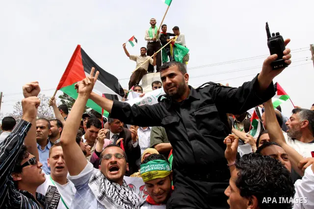 Palestinians wave with national flag and shout slogans during a rally celebrating the signing of a reconciliation deal in Gaza city on May 4,2011. Hundreds of Palestinians have gathered to cheer on a unity agreement bein...