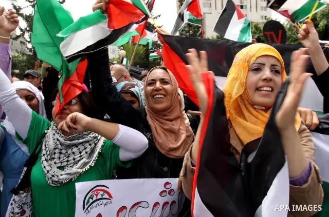 Palestinians wave with national flag and shout slogans during a rally celebrating the signing of a reconciliation deal in Gaza city on May 4,2011. Hundreds of Palestinians have gathered to cheer on a unity agreement bein...